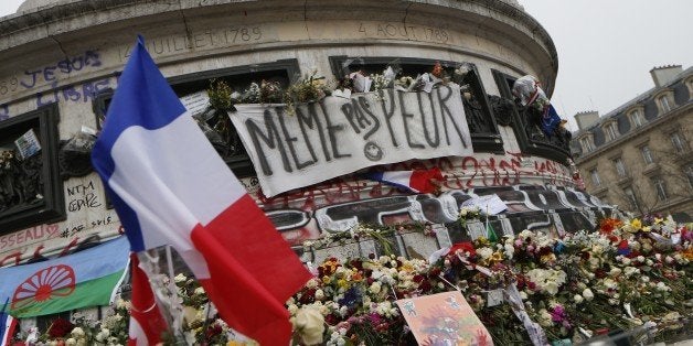 A picture taken on November 27, 2015, shows French national flags, candles and flowers at a makeshift memorial in Place de la