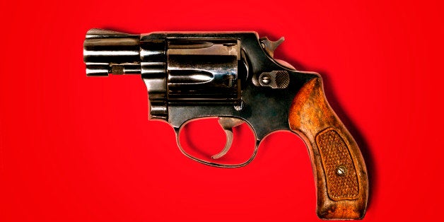 Hand gun against red background, close-up