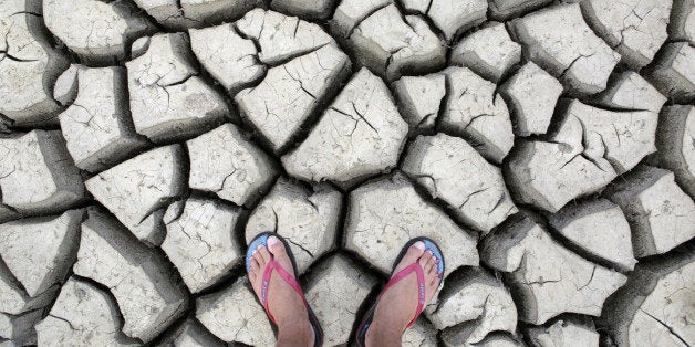 Large cracks in rock hard earth of water hole during dry season drought.