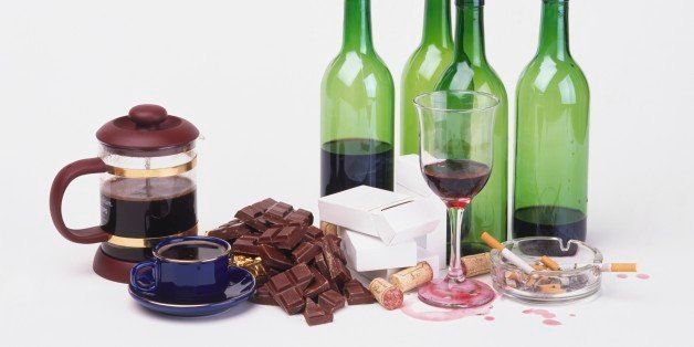 Coffee pot, cup of black coffee, chocolate, cigarettes, glass and bottles of wine and corks.