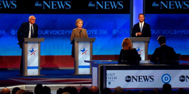 Bernie Sanders, left, Hillary Clinton, center, and Martin OâMalley take the stage for a Democratic presidential primary debate Saturday, Dec. 19, 2015, at Saint Anselm College in Manchester, N.H. Seated at the table are debate moderators Martha Raddatz, left, and David Muir, of ABC News. (AP Photo/Jim Cole)