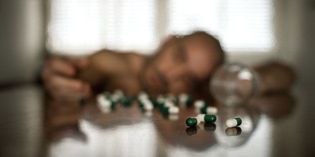 Unconscious man lying the head on table due to overdose of drugs.