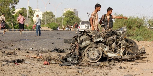 Fighters loyal to Yemen's President Abedrabbo Mansour Hadi look at the remains of a vehicle following a car bomb attack that targeted a convey of three senior south Yemeni officials in the Inma district, north of the the southern Yemeni city of Aden, on January 4, 2016. Newly appointed Aden Governor Aidarus al-Zubaidi, city police chief General Shallal Ali Shayae and the governor of neighbouring Lahj province, Naser al-Khubaj, survived the attack as they were returning from a visit to a camp of Emirati troops taking part in the Saudi-led coalition that has been battling Iran-backed rebels in Yemen since March, the sources said. AFP PHOTO / SALEH AL-OBEIDI / AFP / SALEH AL-OBEIDI (Photo credit should read SALEH AL-OBEIDI/AFP/Getty Images)