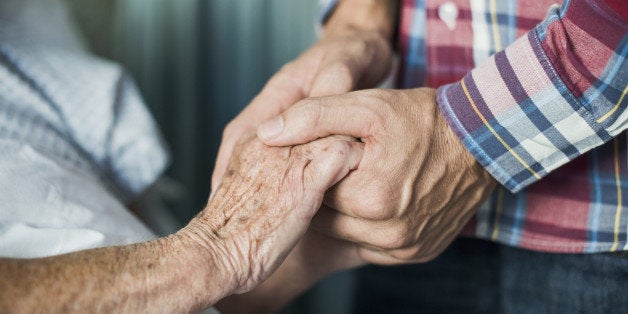 Close up of son holding his mothers hands in hospital