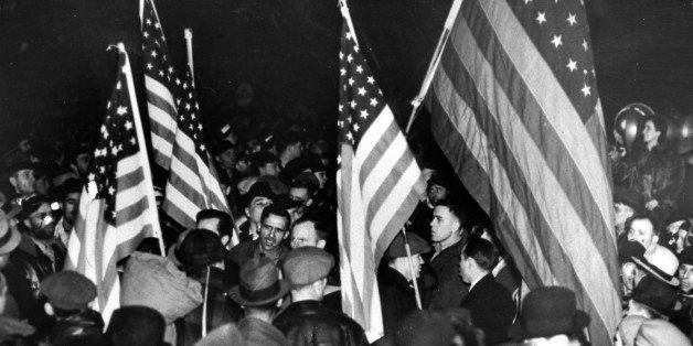 FILE - This Feb. 12, 1937 photo shows strikers at the General Motors Fisher body plant in Flint, Mich., waving U.S. flags during the Great Depression. General Motors survived wars, strikes and the Great Depression churning out Chevys, Cadillacs and other vehicles that often defined their owners' status in life. But less than a year into its second 100 years, it's coming to the end of a road, ushered by the government into bankruptcy protection. (AP Photo/File)