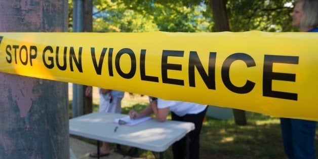 Members of the Coalition of Gun Violence Prevention sign-in behind their version of 'Police Line' perimeter tape, for their monthly protest outside the National Rifle Association(NRA) headquarters August 14, 2014, in Fairfax, Virginia. The group has been protesting monthly on the doorstep of the NRA for a year and half calling for common-sense legislative gun reforms. AFP PHOTO/Paul J. Richards (Photo credit should read PAUL J. RICHARDS/AFP/Getty Images)