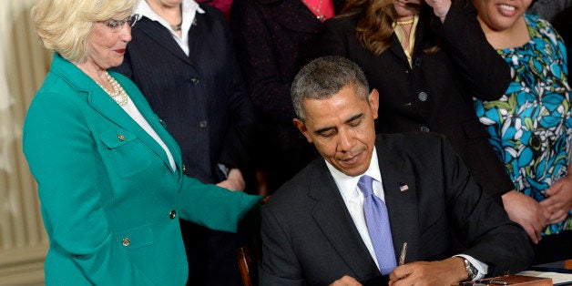 President Barack Obama signs executive actions, with pending Senate legislation, aimed at closing a compensation gender gap that favors men, in the East Room of the White House in Washington, Tuesday, April 8, 2014, during an event marking Equal Pay Day. Obama announced new executive actions to strengthen enforcement of equal pay laws for women. The president and his Democratic allies in Congress are making a concerted election-year push to draw attention to women's wages. Lilly Ledbetter watches at left. (AP Photo/Susan Walsh)