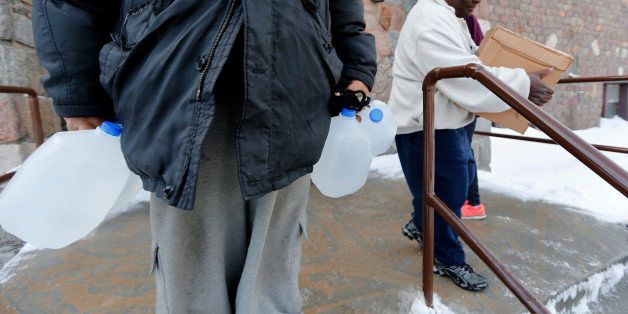 Residents carry free water being distributed at the Lincoln Park United Methodist Church in Flint, Mich., Tuesday, Feb. 3, 2015. The city gets tap water from the Flint River, but residents have complained about the smell, taste and appearance. The city says the water is safe to drink. The federal government, however, has cited Flint for high levels of a disinfectant byproduct. (AP Photo/Paul Sancya)