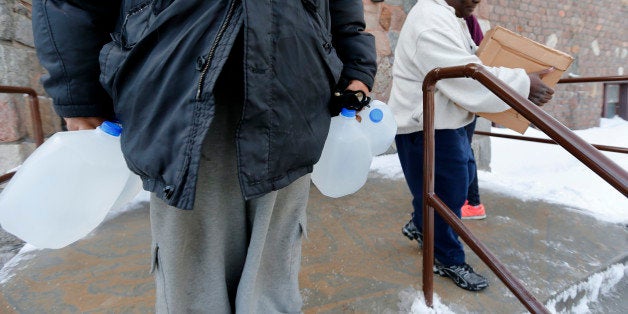 Residents carry free water being distributed at the Lincoln Park United Methodist Church in Flint, Mich., Tuesday, Feb. 3, 20