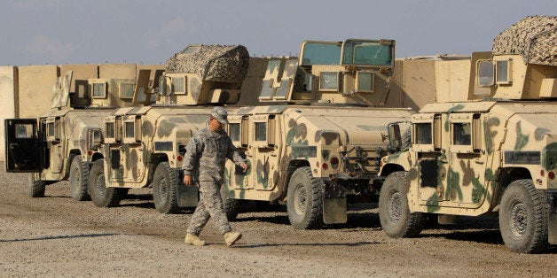 In this Nov. 7, 2011 photo, a U.S. army soldiers walks past military armored vehicles are ready to be shipped out of Iraq at Camp Victory Baghdad, Iraq. Victory Base Complex, as it's formally called by the military, started life as a country club for the Baghdad elite under Saddam. Little reminders of the base's former life such as a sign reminding patrons where to park or when the casino would be open are still located on the base. (AP Photo/Khalid Mohammed)