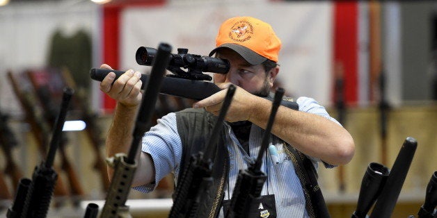 Brendan Walsh looks at a rifle scope in the trade booths showroom during the National Rifle Association's annual meeting in N