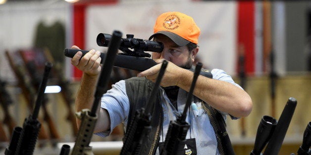 Brendan Walsh looks at a rifle scope in the trade booths showroom during the National Rifle Association's annual meeting in Nashville, Tennessee April 12, 2015. REUTERS/Harrison McClary 