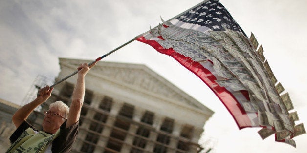 WASHINGTON, DC - OCTOBER 08: David Barrows, of Washington, DC, waves a flag with corporate logos and fake money during a rally against money in politics outside the Supreme Court October 8, 2013 in Washington, DC. On Tuesday, the Supreme Court heard oral arguments in McCutcheon v. Federal Election Committee, a first amendment case that will determine how much money an individual can contribute directly to political campaigns. (Photo by Chip Somodevilla/Getty Images)