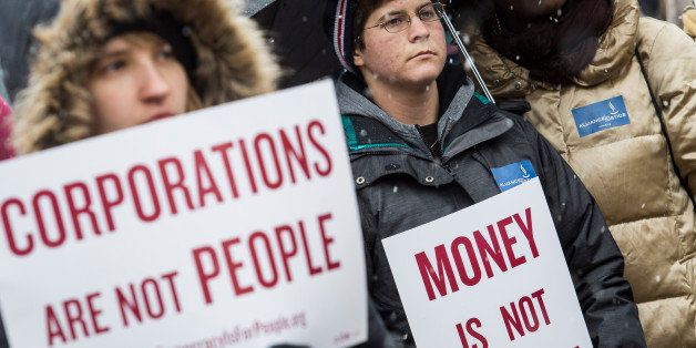 WASHINGTON, DC - JANUARY 21: Attendees hold signs as they listen to speakers during a rally calling for an end to corporate money in politics and to mark the fifth anniversary of the Supreme Court's Citizens United decision, at Lafayette Square near the White House, January 21, 2015 in Washington, DC. Wednesday is the fifth anniversary of the landmark ruling, which paved the way for additional campaign money from corporations, unions and other interests and prevented the government from setting limits on corporate political spending. (Photo by Drew Angerer/Getty Images)