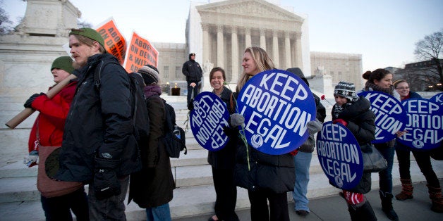 Bettina Hager, center, and Jeff Foster, left, join a candlelight vigil in front of the U.S. Supreme Court in Washington, to