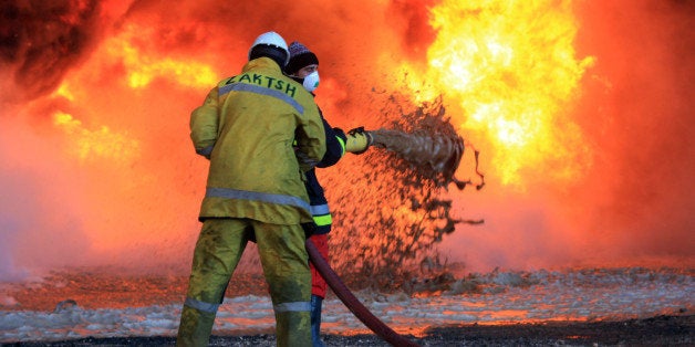 Libyan oil workers try to extinguish flames at an oil facility in northern Libya's Ras Lanouf region after it was set ablaze following fresh attacks launched by Islamic State (IS) group jihadists to seize key port terminals, on January 21, 2016. Fighting broke out at dawn in the Ras Lanouf region, which along with the nearby Al-Sidra facility is one of the country's main oil export hubs, said the National Oil Corporation (NOC). / AFP / STRINGER (Photo credit should read STRINGER/AFP/Getty Images)