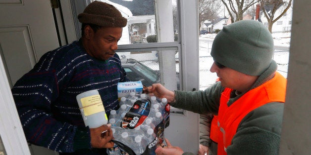 Louis Singleton receives water filters, bottled water and a test kit from Michigan National Guard Specialist Joe Weaver as clean water supplies are distributed to residents, Thursday, Jan. 21, 2016 in Flint, Mich. The National Guard, state employees, local authorities and volunteers have been distributing lead tests, filters and bottled water during the city's drinking water crisis. (AP Photo/Paul Sancya)