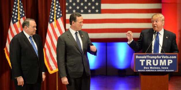 Donald Trump (R) speaks as Rick Santorm (C) as Mike Huckabee (L) look on during a Trump campaign rally raising funds for US military veterans at Drake University in Des Moines, Iowa on January 28, 2016. US Republicans scrambling to win the first contest in the presidential nomination race were gearing for battle at high-profile debate in Iowa, but frontrunner Donald Trump is upending the campaign by defiantly refusing to attend. Trump's gamble has left the presidential race in uncharted waters just days before Iowans vote on February 1, insisting he will not back down in his feud with debate host Fox News.Instead, the billionaire has doubled down, hosting a rogue, rival event for US military veterans at the same time that his own party is showcasing its candidates for president to all-important Iowa voters. / AFP / William EDWARDS (Photo credit should read WILLIAM EDWARDS/AFP/Getty Images)