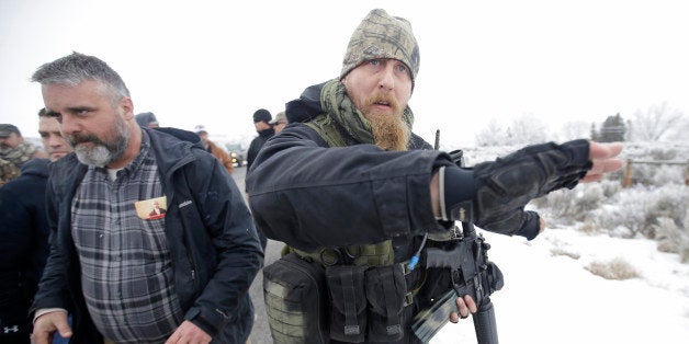 A man standing guard pushes the media aside after members of the "3% of Idaho" group along with several other organizations arrived at the Malheur National Wildlife Refuge Saturday, Jan. 9, 2016, near Burns, Ore. A small, armed group has been occupying a remote national wildlife refuge in Oregon for a week to protest federal land use policies. (AP Photo/Rick Bowmer)