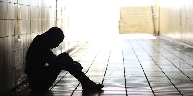 Backlight of a teenager depressed sitting inside a dirty tunnel