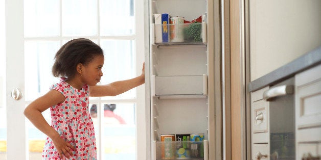 Girl (4-6) looking in kitchen fridge