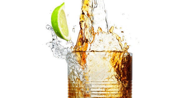 Making a big party splash of a mixture of a stream of clean clear alcohol and a stream of brown cola splashing and mixing a r