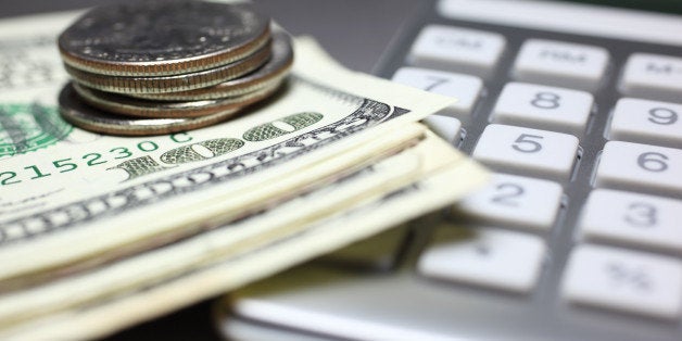 Close-up of a calculator, stack of coins and one hundred US dollar bills.