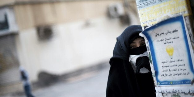 A Bahraini protester takes cover during clashes with riot police following a protest against the arrest of Sheikh Ali Salman