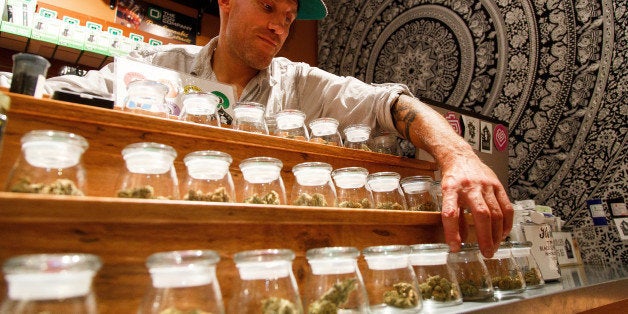 Shane Cavanaugh, owner of Amazon Organics, a pot dispensary in Eugene, Ore., arranges the cannabis display in his store on M