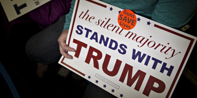 An attendee holds a campaign sign with a 'Guns Save Lives' sticker affixed to it before the start of a campaign rally for Donald Trump, president and chief executive of Trump Organization Inc. and 2016 Republican presidential candidate, at the Radford University Dedmon Arena in Radford, Virginia, U.S., on Monday, Feb. 29, 2016. The single biggest day of voting in the Republican primary is March 1, Super Tuesday, when nearly half of the delegates needed to secure the nomination are up for grabs with Trump favored in most of these contests. Photographer: Andrew Harrer/Bloomberg via Getty Images