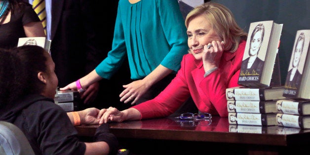 HiIlary Rodham Clinton, right, listens before signing a copy of her new book for a wheelchair-bound woman on Tuesday June 10, 2014, at Barnes and Noble bookstore in New York. Clinton said Tuesday that she and former President Bill Clinton "fully appreciate how hard life is for so many Americans," seeking to refine remarks she made about the pair being broke when they left the White House while on a high-profile media tour for a new book. (AP Photo/Bebeto Matthews)