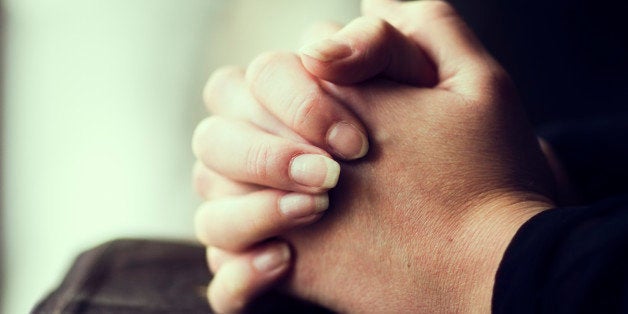 A close-up of a christian woman folding hands on the bible.