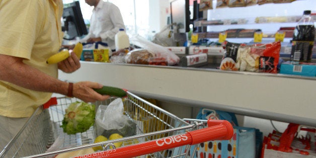 A customer unloads items from his shopping cart at a checkout counter in a Coles supermarket, operated by Wesfarmers Ltd., in