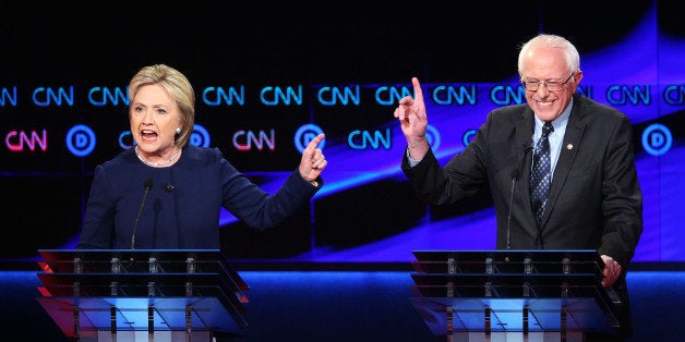 FLINT, MI - MARCH 06: Democratic presidential candidate Senator Bernie Sanders (D-VT) and Democratic presidential candidate Hillary Clinton speak during the CNN Democratic Presidential Primary Debate at the Whiting Auditorium at the Cultural Center Campus on March 6, 2016 in Flint, Michigan. Voters in Michigan will go to the polls March 8 for the state's primary. (Photo by Scott Olson/Getty Images)