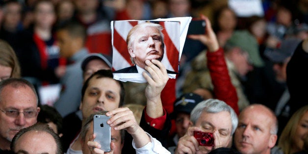 A supporter of Republican presidential candidate Donald Trump holds up a photo of Trump during a rally Sunday, March 13, 2016