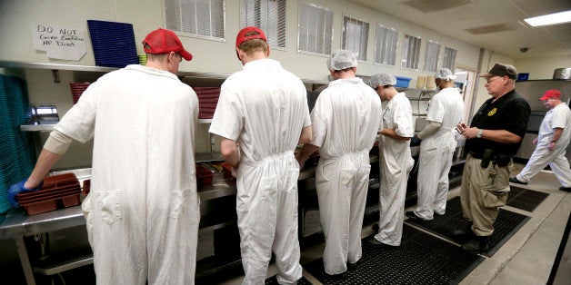 In this photo taken Tuesday, Dec. 8, 2015, corrections officer Kevin Cranston watches inmates working in the kitchen at the Ellsworth Correctional Facility in Ellsworth, Kan. Low wages among Kansas corrections officers are causing many to leave the field, leaving about 9 percent of the positions in the state's prisons unfilled. (AP Photo/Charlie Riedel)