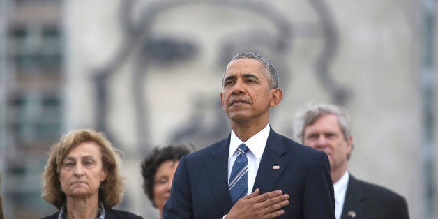 Back dropped by a monument depicting Cuba's revolutionary hero Ernesto "Che" Guevara, U.S. President Barack Obama listens to