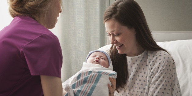 Caucasian mother holding newborn in hospital