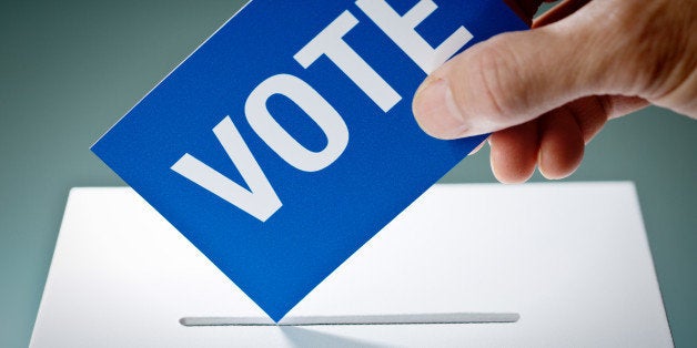 Voter's hand holding election ballot for the U.S. Democratic Party, inserting the vote into the ballot box. Concept image of