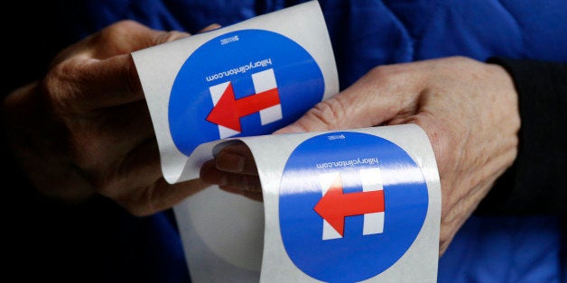 A Hillary Clinton supporter hands out stickers for her campaign during a Democratic caucus Saturday, March 26, 2016, in Seattle. Democrats caucused statewide in support of either Clinton or Bernie Sanders, with the 101 delegates at stake to be awarded proportionally. (AP Photo/Elaine Thompson)