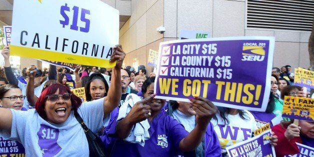 Workers celebrate outside the Ronald Reagan State Building in downtown Los Angeles, where California Governor Jerry Brown signed the bill that will raise the state's minimum wage to $15 an hour by 2022 while surrounded by supporters and politicians in Los Angeles, California on April 4, 2016. / AFP / FREDERIC J. BROWN (Photo credit should read FREDERIC J. BROWN/AFP/Getty Images)