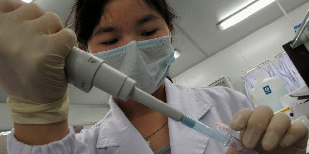 A researcher inserts a sample into a receptacle inside the "DNA Lab" at the Beijing Genomics Institute in Shenzhen, southern
