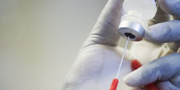 Close up of hand in rubber glove filling syringe