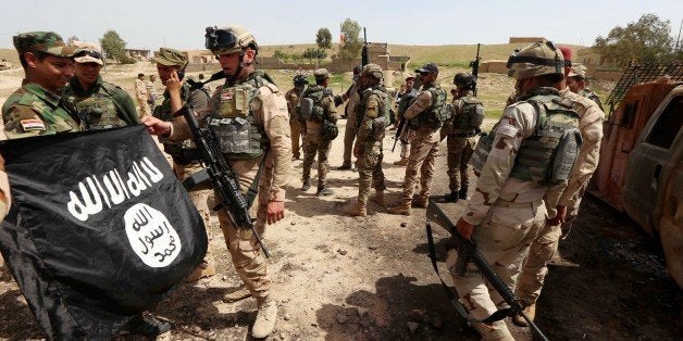 Iraqi soldiers hold a flag that they seized from the Islamic State group (IS) as they hold a position near the frontline on April 9, 2016 in the town of Kharbardan, located 10 kilometres (6 miles) south of Qayyarah, during military operations to recapture the northern Nineveh province from IS jihadists. Iraqi army troops and allied paramilitary fighters on March 24 launched a major offensive aimed at retaking the northern Nineveh province, the capital of which, Mosul, is the main hub of IS in Iraq. Qayyarah is about 60 kilometres (35 miles) south of Mosul. / AFP / SAFIN HAMED (Photo credit should read SAFIN HAMED/AFP/Getty Images)