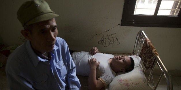 Nguyen Hong Phuc, a 63-year-old former soldier, sits on the bed with his son Nguyen Dinh Loc, 20, who is recovering from a recent tumour surgery at Friendship Village outside Hanoi April 8, 2015. Nguyen Dinh Loc has serious mental and physical problems that his family and doctors link to his father's exposure to Agent Orange. His father joined the military after the U.S. army stopped using Agent Orange in 1971, but lived in areas heavily contaminated by it, including near Danang airport, where the chemical defoliant was stored. REUTERS/Damir Sagolj