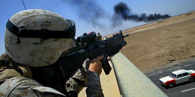 FALLUJAH, IRAQ: An US soldier from 2nd Battalion, 1st Marines, takes position on a bridge over a highway inspecting a plume of black smoke on the outskirts of the Sunni Muslim city of Fallujah, 50km west of Baghdad, 07 June 2004. It is unknown what caused the smoke. AFP PHOTO/Mauricio LIMA (Photo credit should read MAURICIO LIMA/AFP/Getty Images)