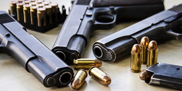 Three pistols laying on table with bullets