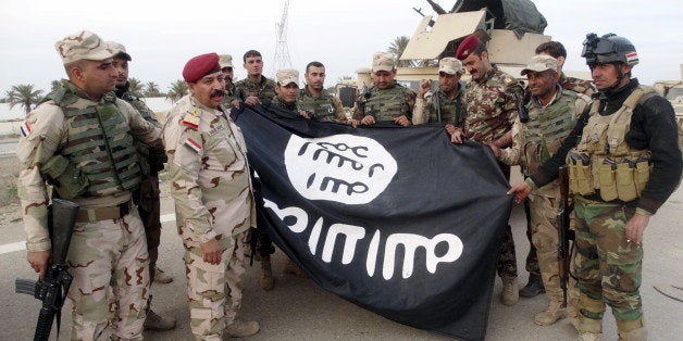 Iraqi security forces stand with an Islamic State flag which they pulled down in the city of Ramadi, February 1, 2016. Pictur