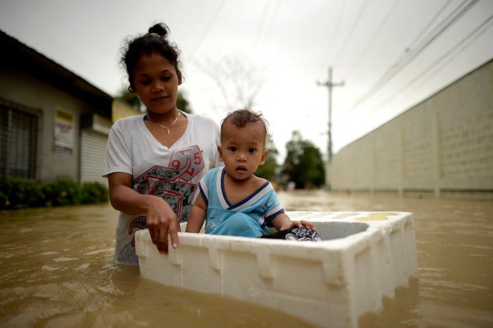 Lovelyn Cesar, 22, carries her one year old baby Matthew as she cross a flooded street in a suburb of Manila after two histor