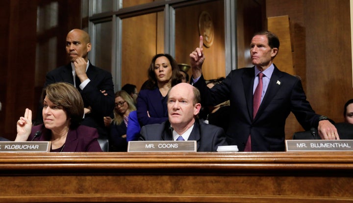 U.S. Senate Judiciary Committee Democratic member Chris Coons speaks while his colleagues Sens. Amy Klobuchar and Richard Blumenthal raise their hands to be heard on the deal made to secure the "yes" vote of Republican Sen. Jeff Flake (not shown) while Sens. Cory Booker and Kamala Harris look on.